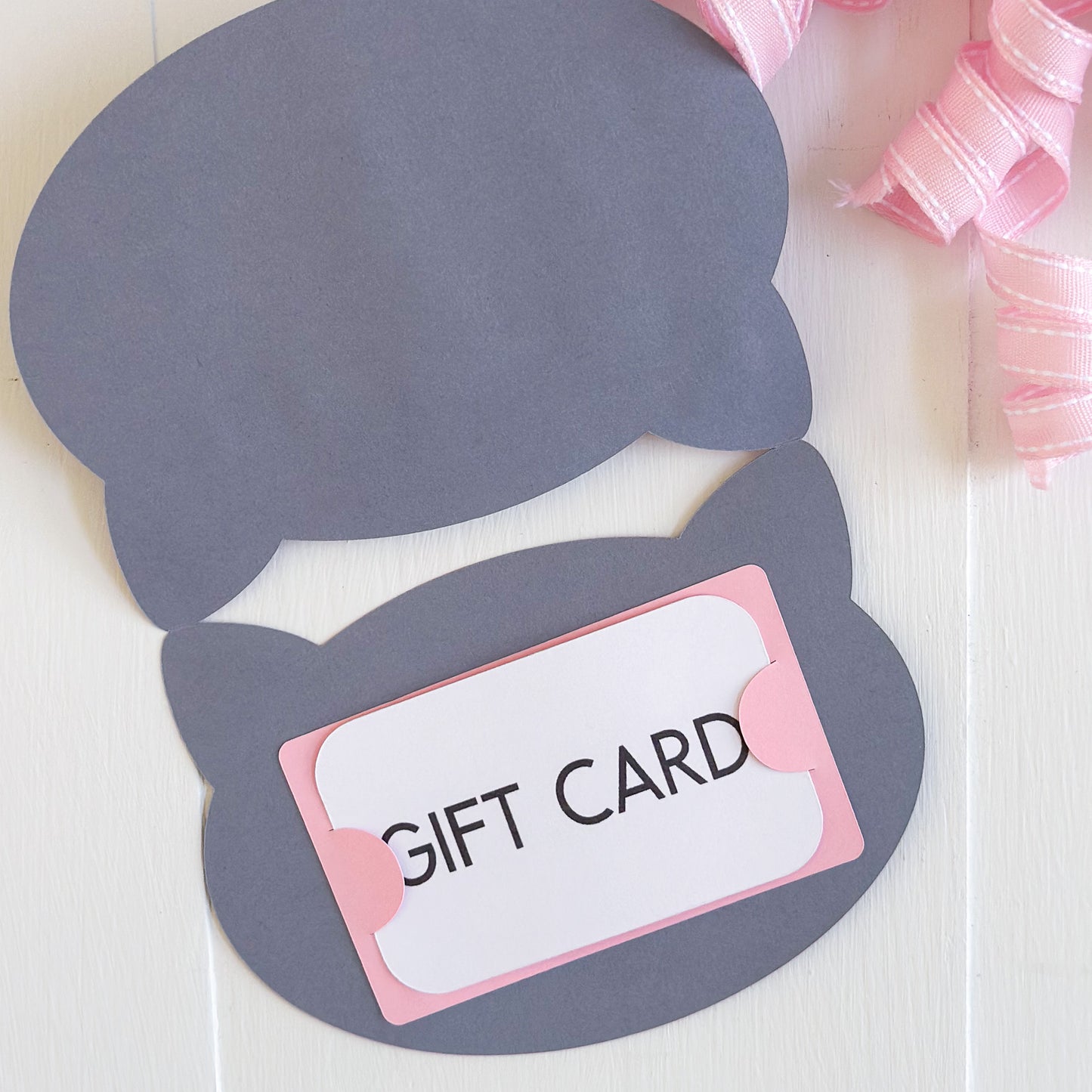 Gray cat-shaped gift card holder with a pink bow on a white background