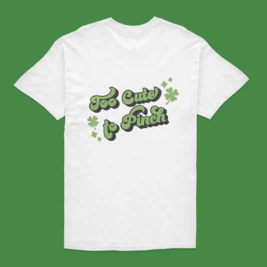 White t-shirt with 'Too Cute to Pinch' text and shamrock design on a green background