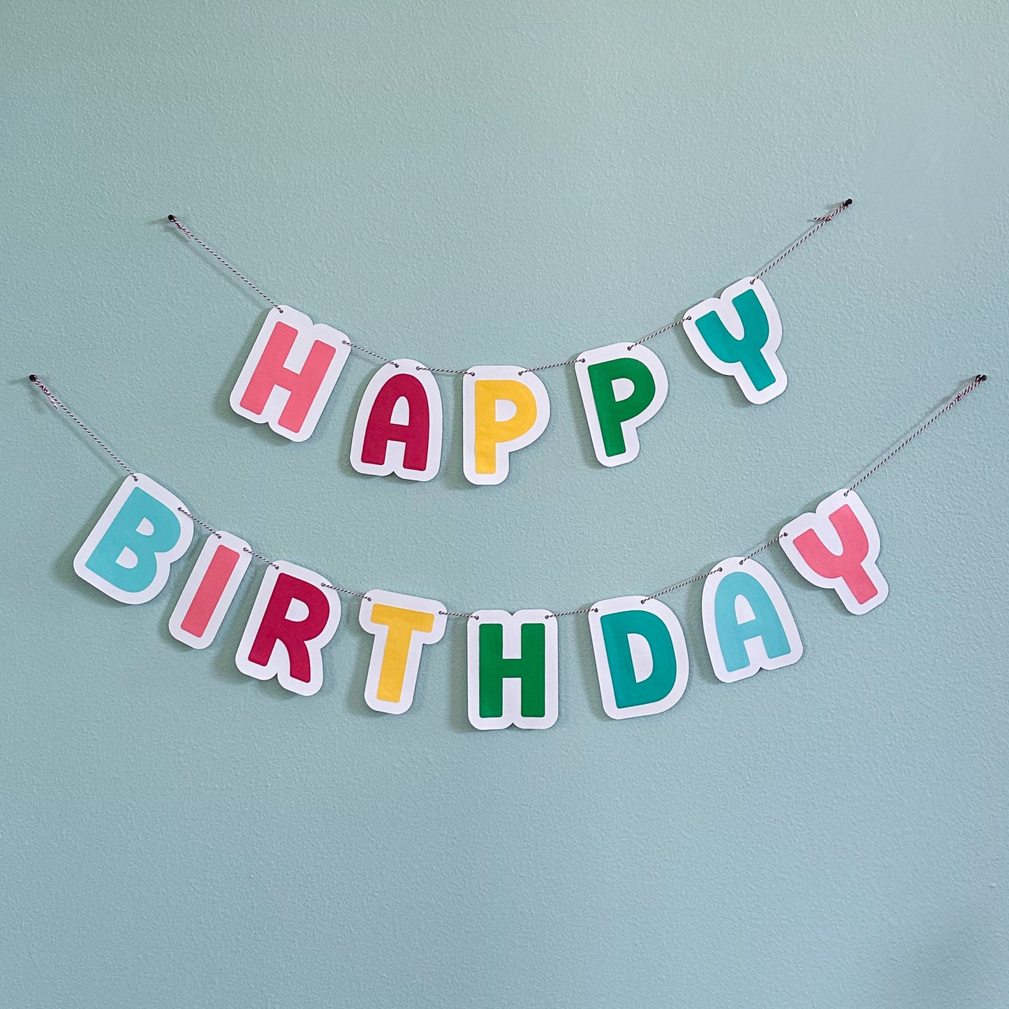 Colorful paper 'Happy Birthday' banner on a light blue background