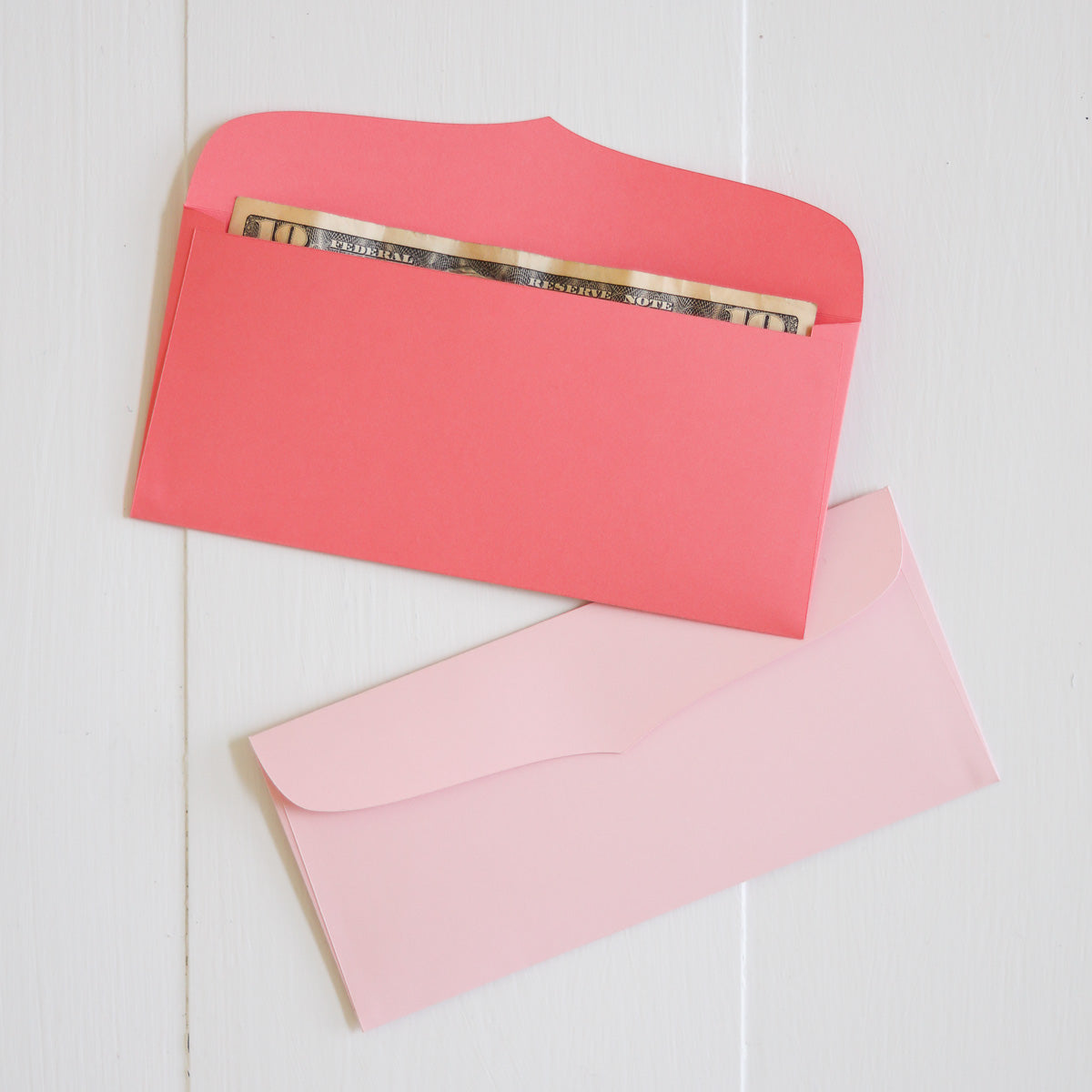 Two pink envelopes on a light wooden surface