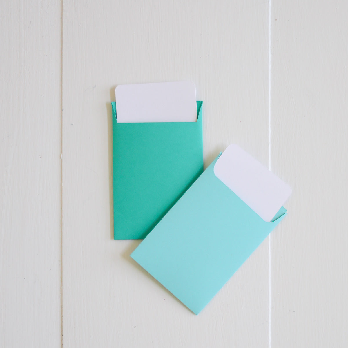 Two turquoise envelopes with gift cards on a white background