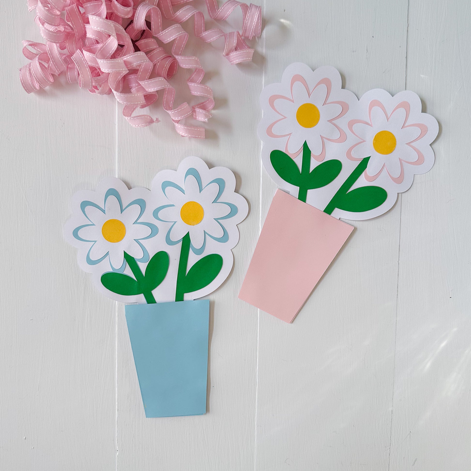 Paper flower gift card holders with pink ribbons on a white background