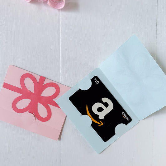 Amazon gift card in a blue envelope with a pink bow on a white background