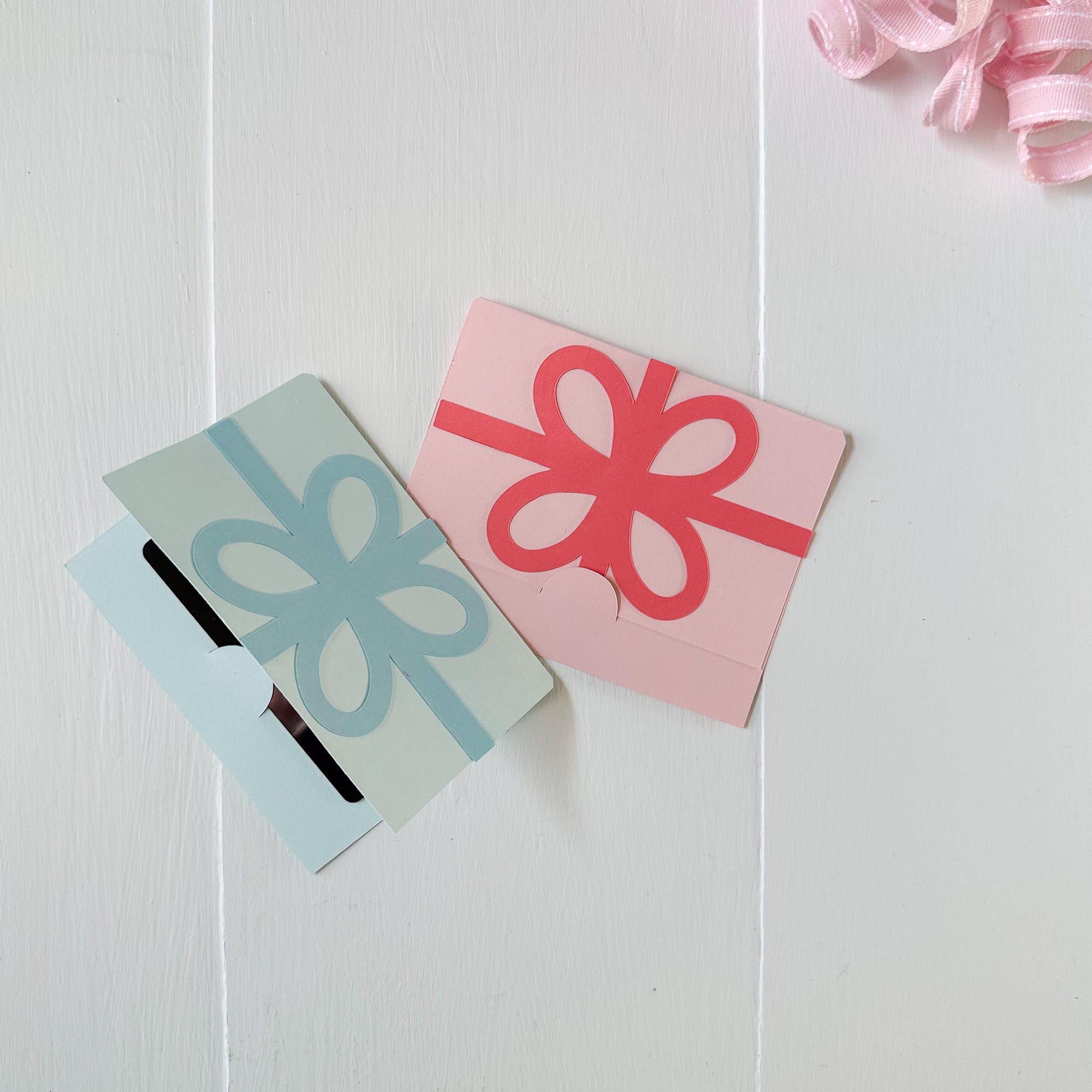 Two paper cutout gift cards holders with decorative bows on a white background